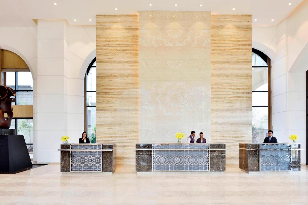 a lobby with a large stone wall with people sitting at tables at Courtyard by Marriott Bengaluru Hebbal in Bengaluru