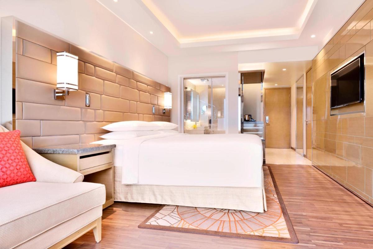 a bedroom with a large white bed and a couch at Courtyard by Marriott Bengaluru Hebbal in Bengaluru