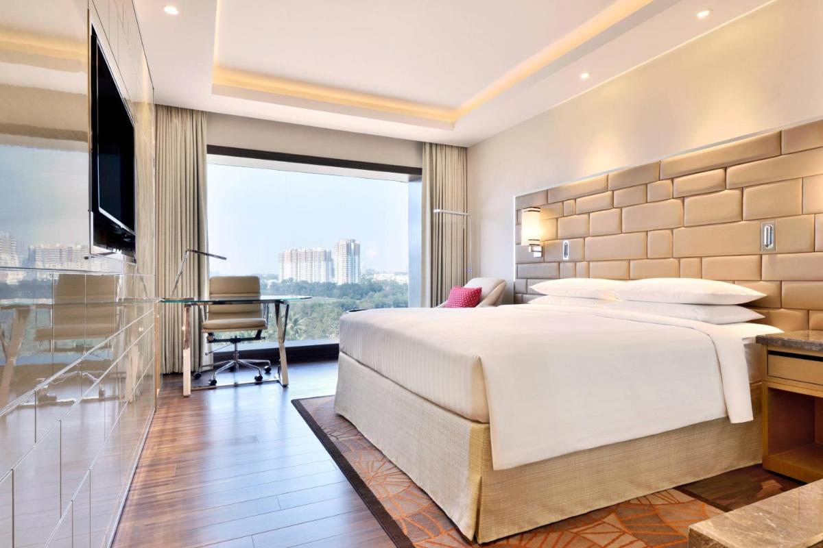 a bedroom with a large white bed and a desk at Courtyard by Marriott Bengaluru Hebbal in Bengaluru