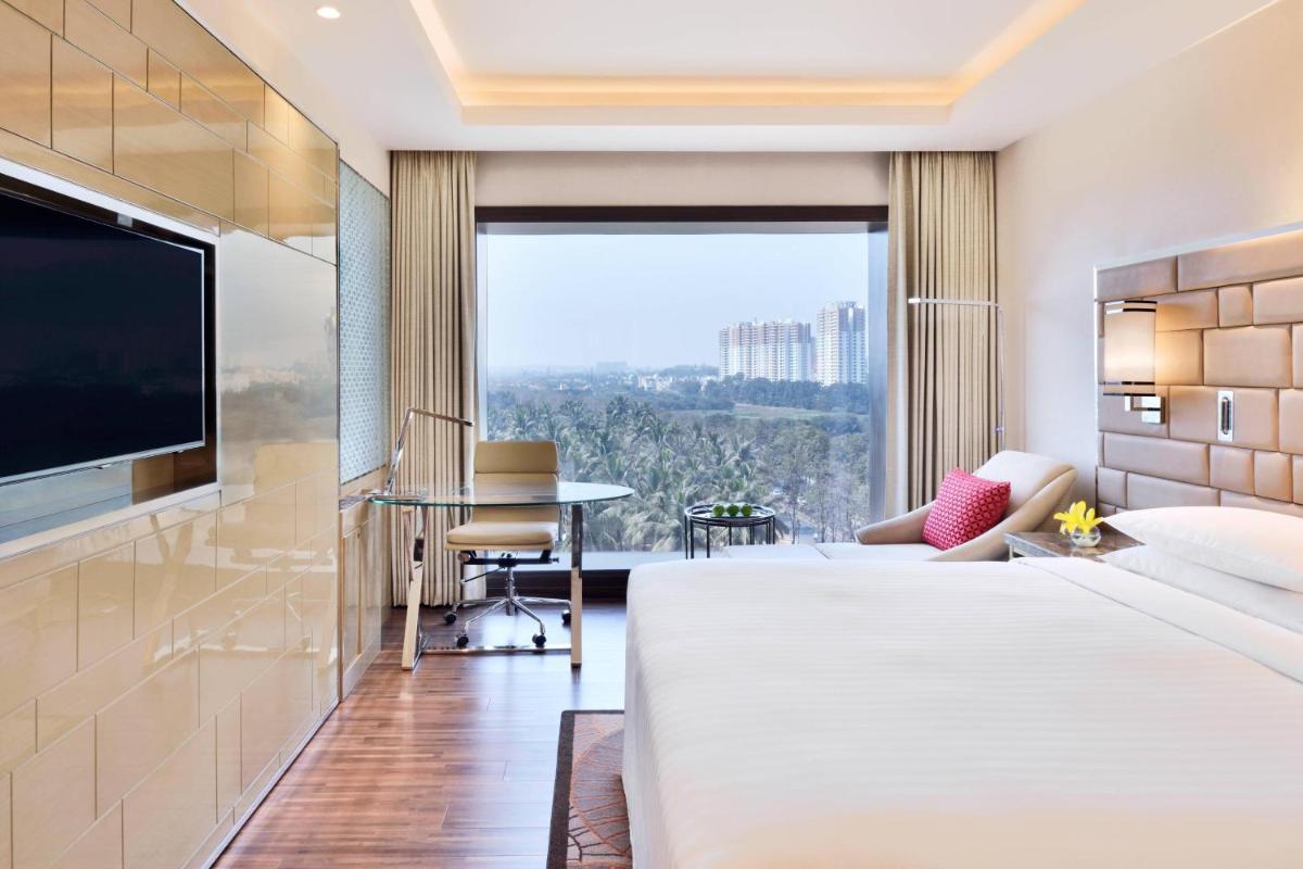 a hotel room with a large bed and a flat screen tv at Courtyard by Marriott Bengaluru Hebbal in Bengaluru