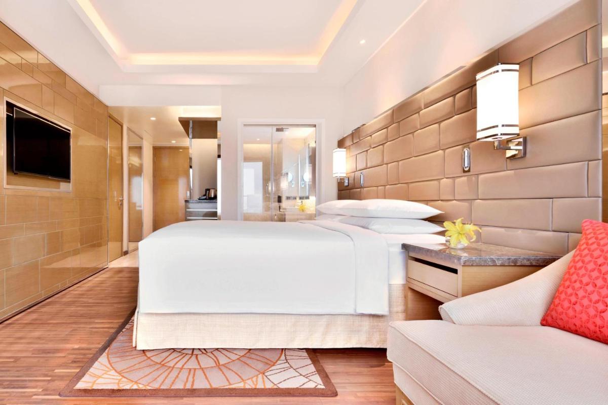a bedroom with a large white bed and a couch at Courtyard by Marriott Bengaluru Hebbal in Bengaluru
