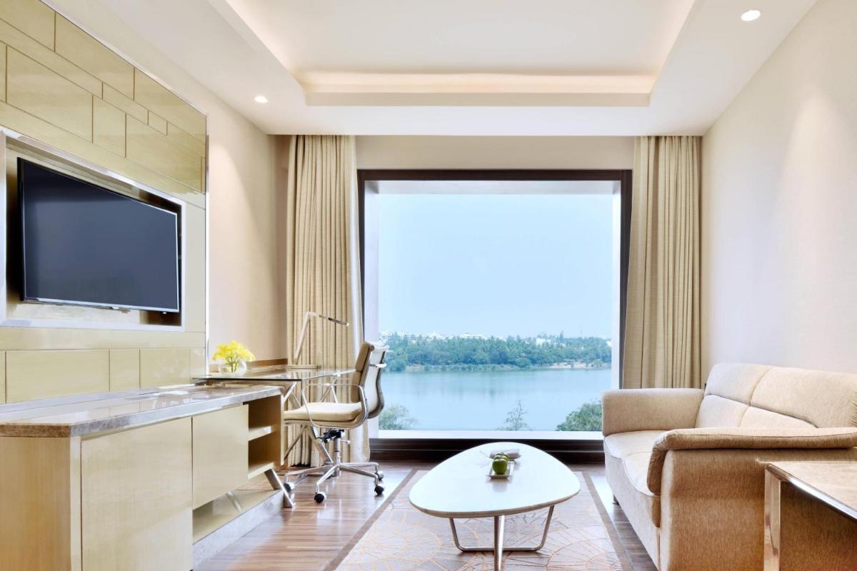 a living room with a couch and a large window at Courtyard by Marriott Bengaluru Hebbal in Bengaluru