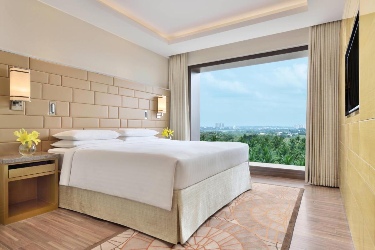 a bedroom with a large bed and a large window at Courtyard by Marriott Bengaluru Hebbal in Bengaluru