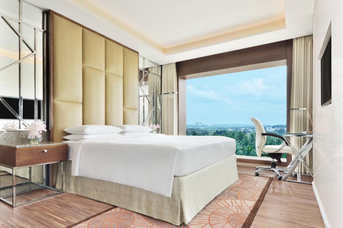 a bedroom with a white bed and a large window at Courtyard by Marriott Bengaluru Hebbal in Bengaluru