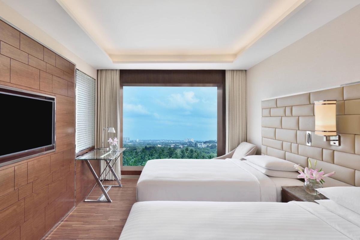 a hotel room with two beds and a flat screen tv at Courtyard by Marriott Bengaluru Hebbal in Bengaluru