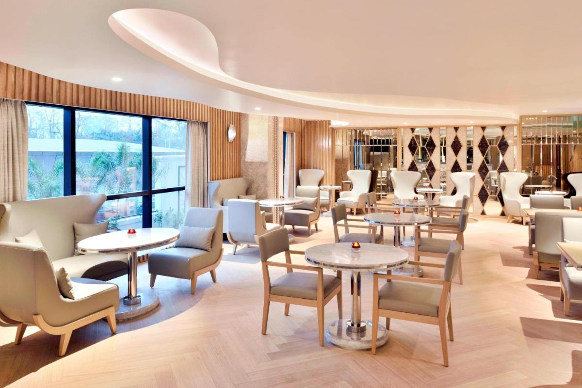 a restaurant with tables and chairs and windows at Courtyard by Marriott Bengaluru Hebbal in Bengaluru