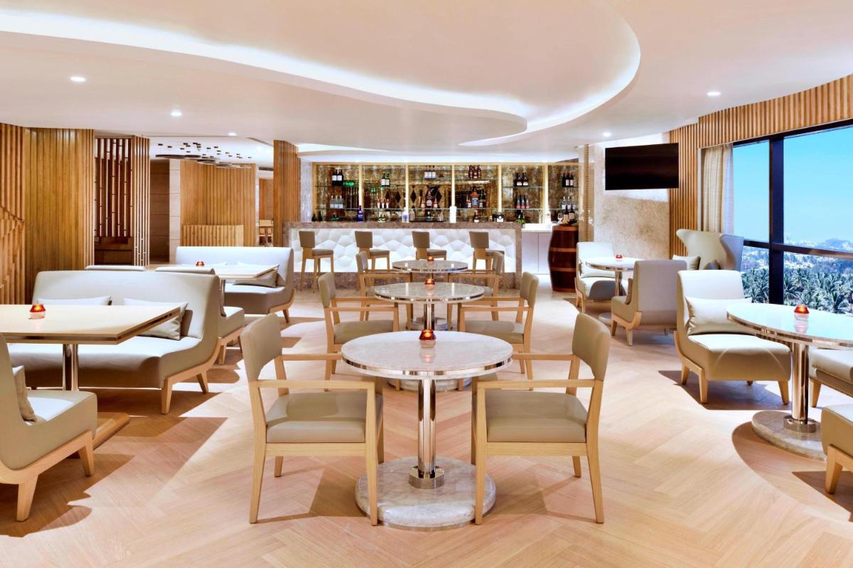 a restaurant with tables and chairs and a bar at Courtyard by Marriott Bengaluru Hebbal in Bengaluru