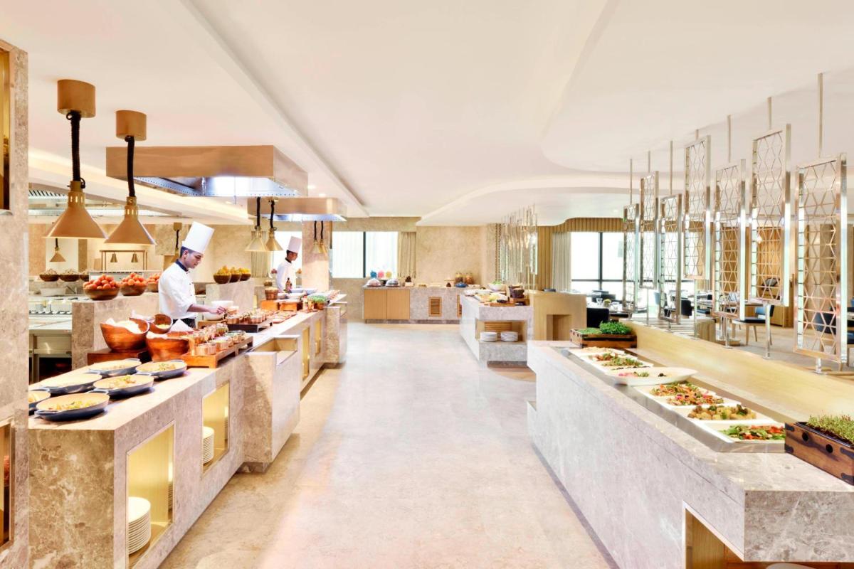 a restaurant with a chef preparing food in a kitchen at Courtyard by Marriott Bengaluru Hebbal in Bengaluru