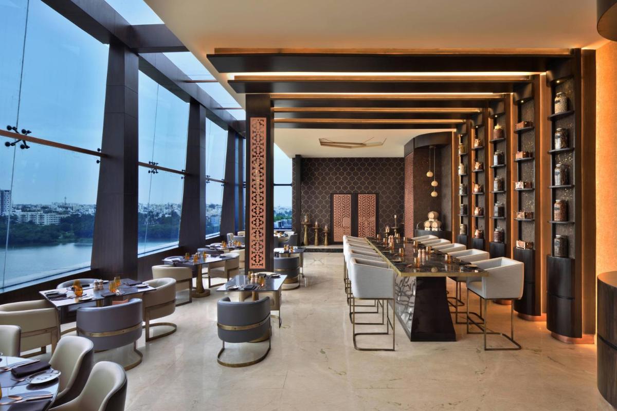 a restaurant with tables and chairs and large windows at Courtyard by Marriott Bengaluru Hebbal in Bengaluru a restaurant with tables and chairs and large windows at Courtyard by Marriott Bengaluru Hebbal in Bengaluru