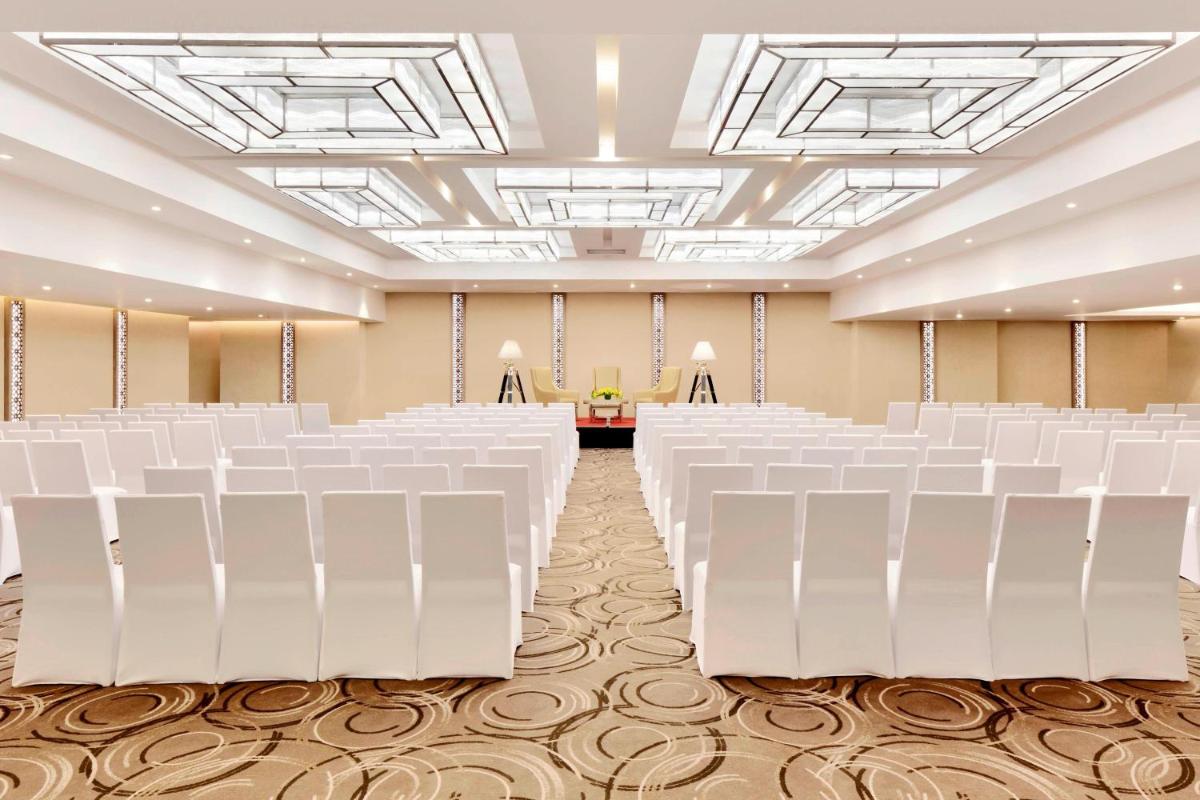 an empty banquet hall with white chairs and a stage at Courtyard by Marriott Bengaluru Hebbal in Bengaluru