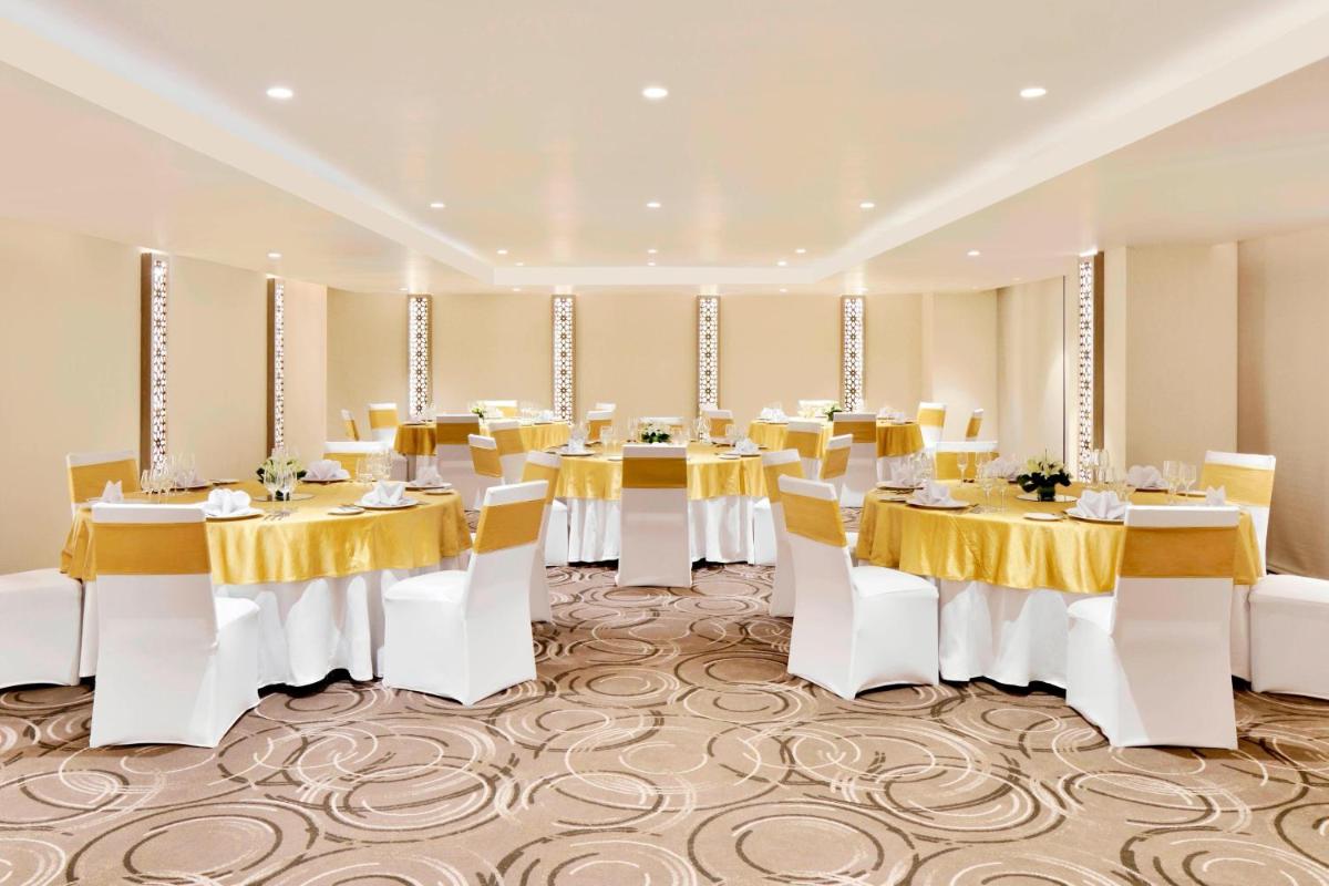 a banquet hall with white tables and yellow tablecloths at Courtyard by Marriott Bengaluru Hebbal in Bengaluru