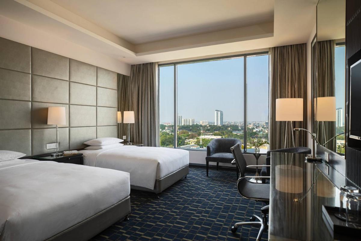 a hotel room with two beds and a large window at Renaissance Bengaluru Race Course Hotel in Bengaluru