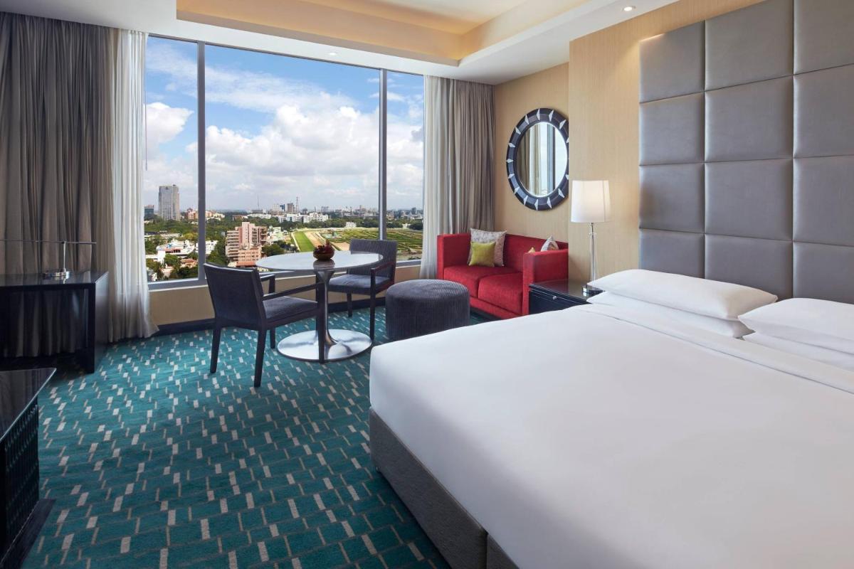 a hotel room with a bed and a table and chairs at Renaissance Bengaluru Race Course Hotel in Bengaluru