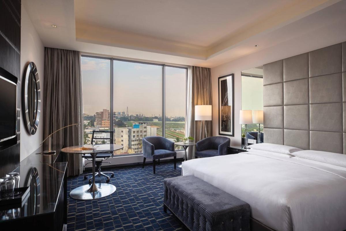 a hotel room with a bed and a large window at Renaissance Bengaluru Race Course Hotel in Bengaluru