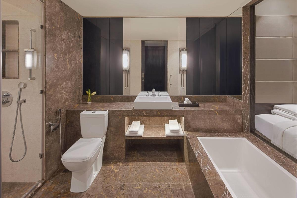 a bathroom with a toilet and a tub and a sink at Renaissance Bengaluru Race Course Hotel in Bengaluru