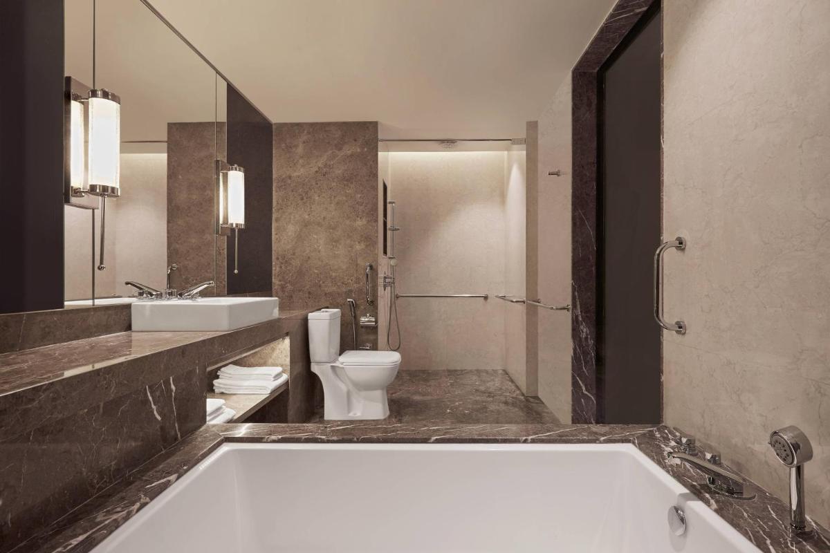 a bathroom with a tub and a toilet and a sink at Renaissance Bengaluru Race Course Hotel in Bengaluru