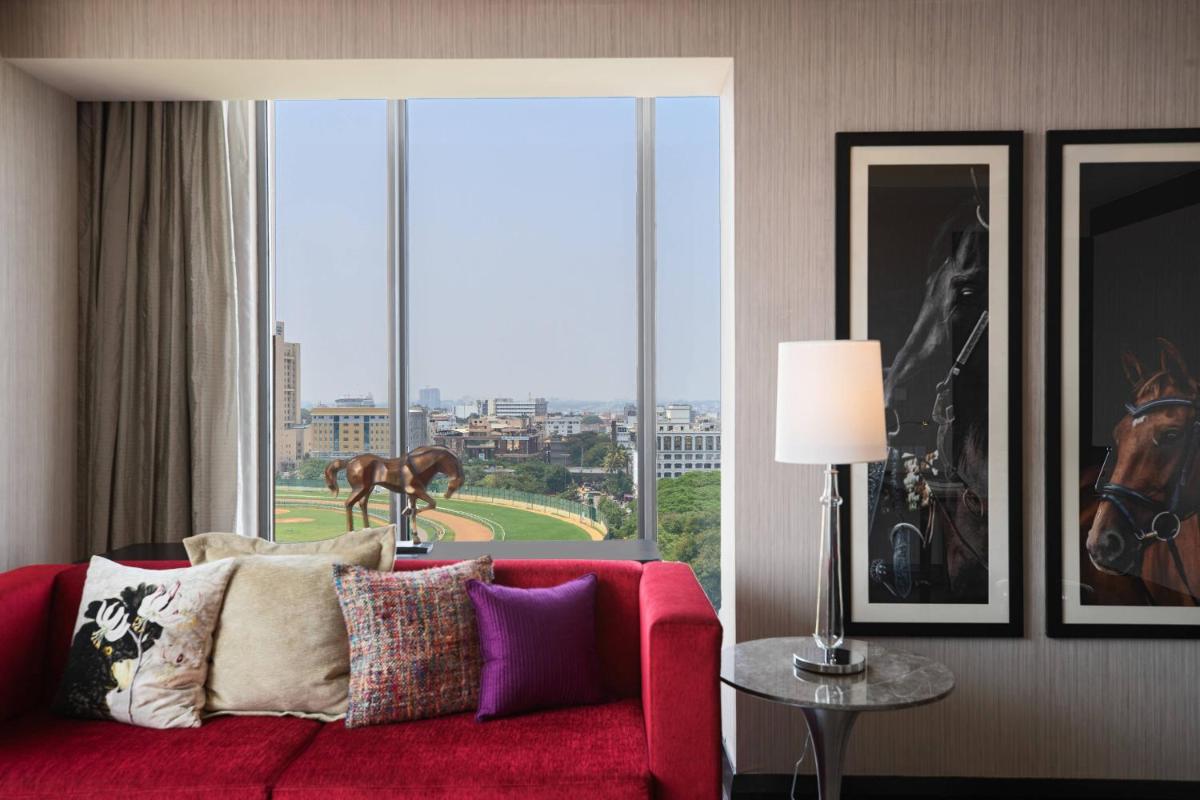 a living room with a red couch and a large window at Renaissance Bengaluru Race Course Hotel in Bengaluru