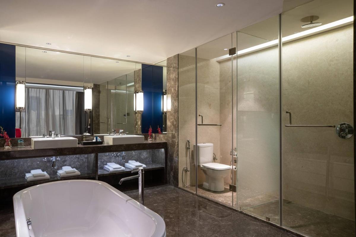 a bathroom with a tub and a shower and a toilet at Renaissance Bengaluru Race Course Hotel in Bengaluru