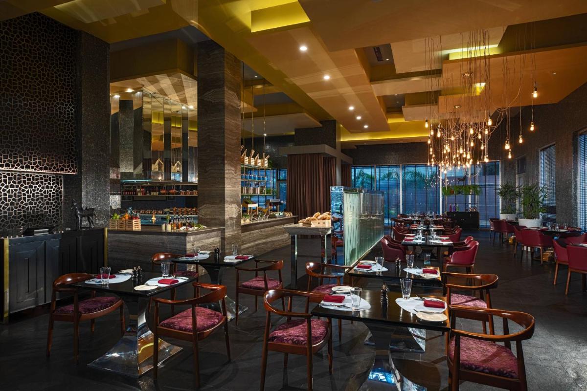 a restaurant with tables and chairs and a bar at Renaissance Bengaluru Race Course Hotel in Bengaluru