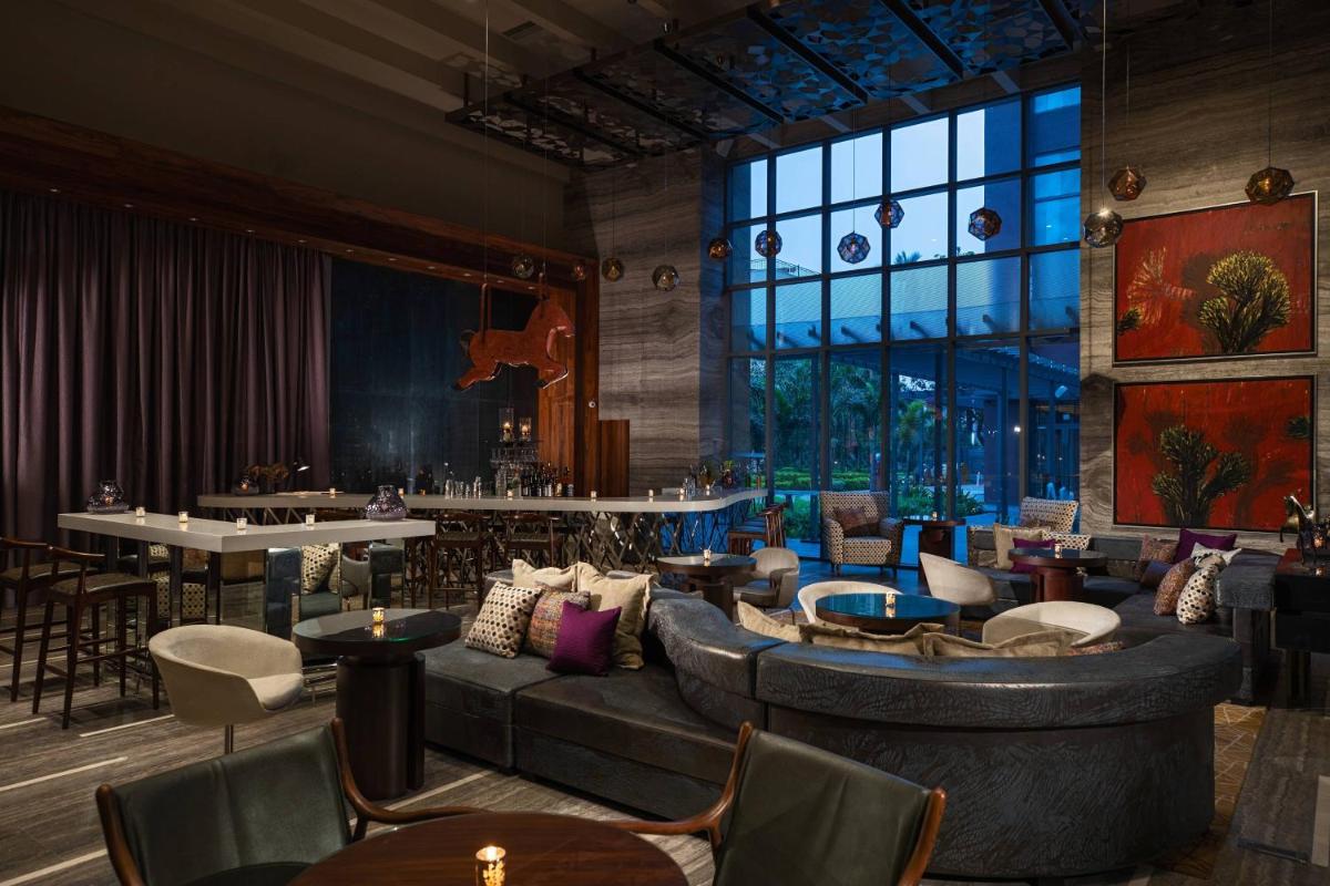 a lobby with a large couch and tables and chairs at Renaissance Bengaluru Race Course Hotel in Bengaluru a lobby with a large couch and tables and chairs at Renaissance Bengaluru Race Course Hotel in Bengaluru