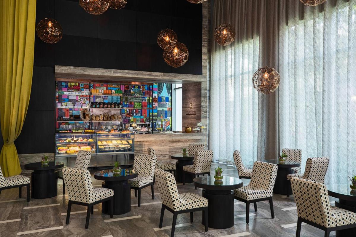 a restaurant with tables and chairs and a counter at Renaissance Bengaluru Race Course Hotel in Bengaluru