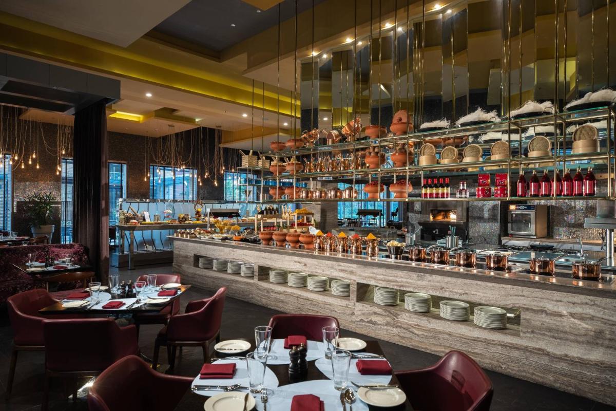 a restaurant with tables and chairs and a bar at Renaissance Bengaluru Race Course Hotel in Bengaluru