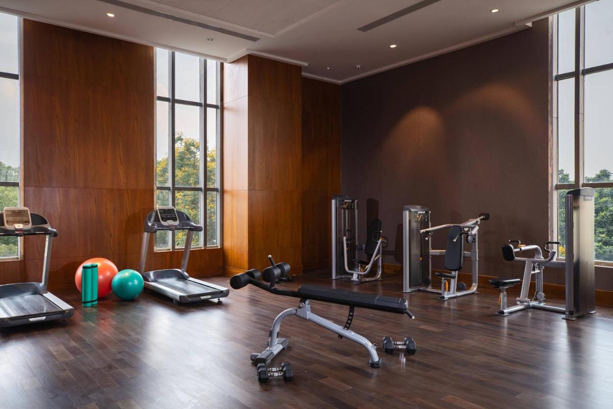 a gym with treadmills and exercise equipment in a room at Renaissance Bengaluru Race Course Hotel in Bengaluru