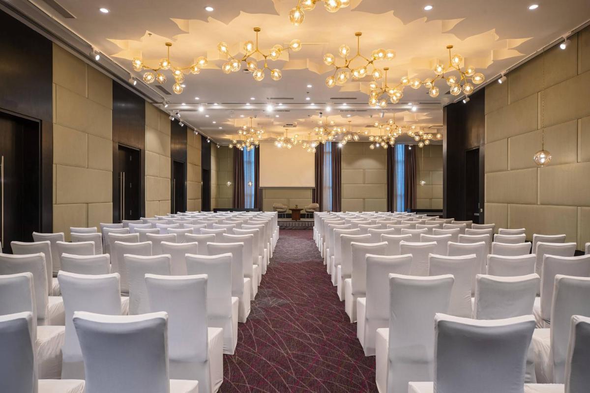 an empty banquet hall with white chairs and chandeliers at Renaissance Bengaluru Race Course Hotel in Bengaluru