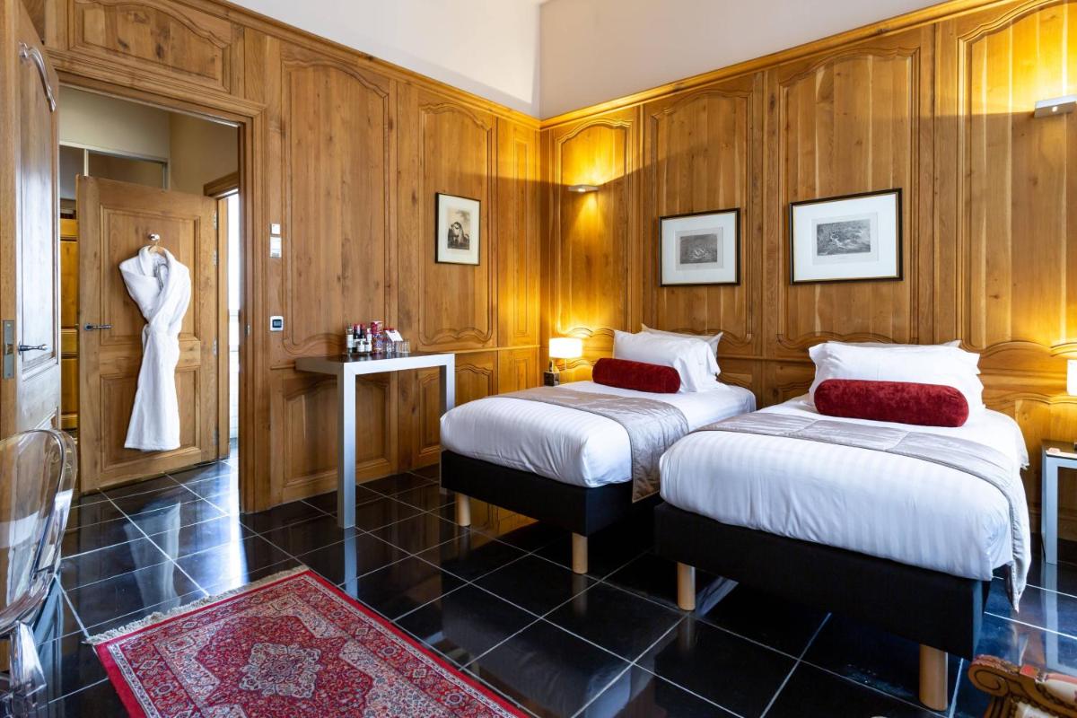 Cette chambre comprend 2 lits et une robe accrochée au mur. dans l'établissement L'Hermitage Gantois, Autograph Collection, à Lille