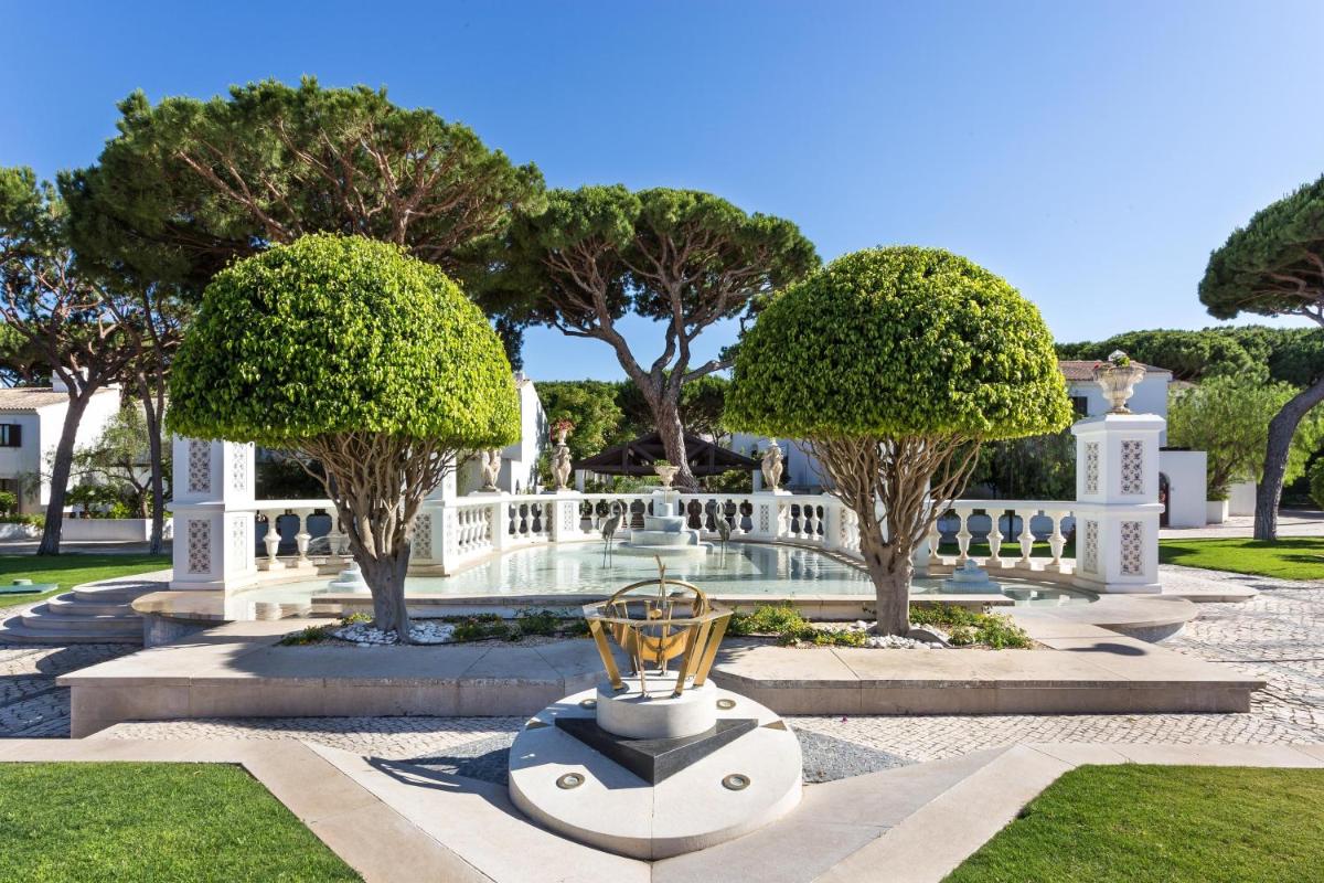 um jardim com árvores e um troféu no meio em Pine Cliffs Ocean Suites, a Luxury Collection Resort & Spa, Algarve em Albufeira um jardim com árvores e um troféu no meio em Pine Cliffs Ocean Suites, a Luxury Collection Resort & Spa, Algarve em Albufeira