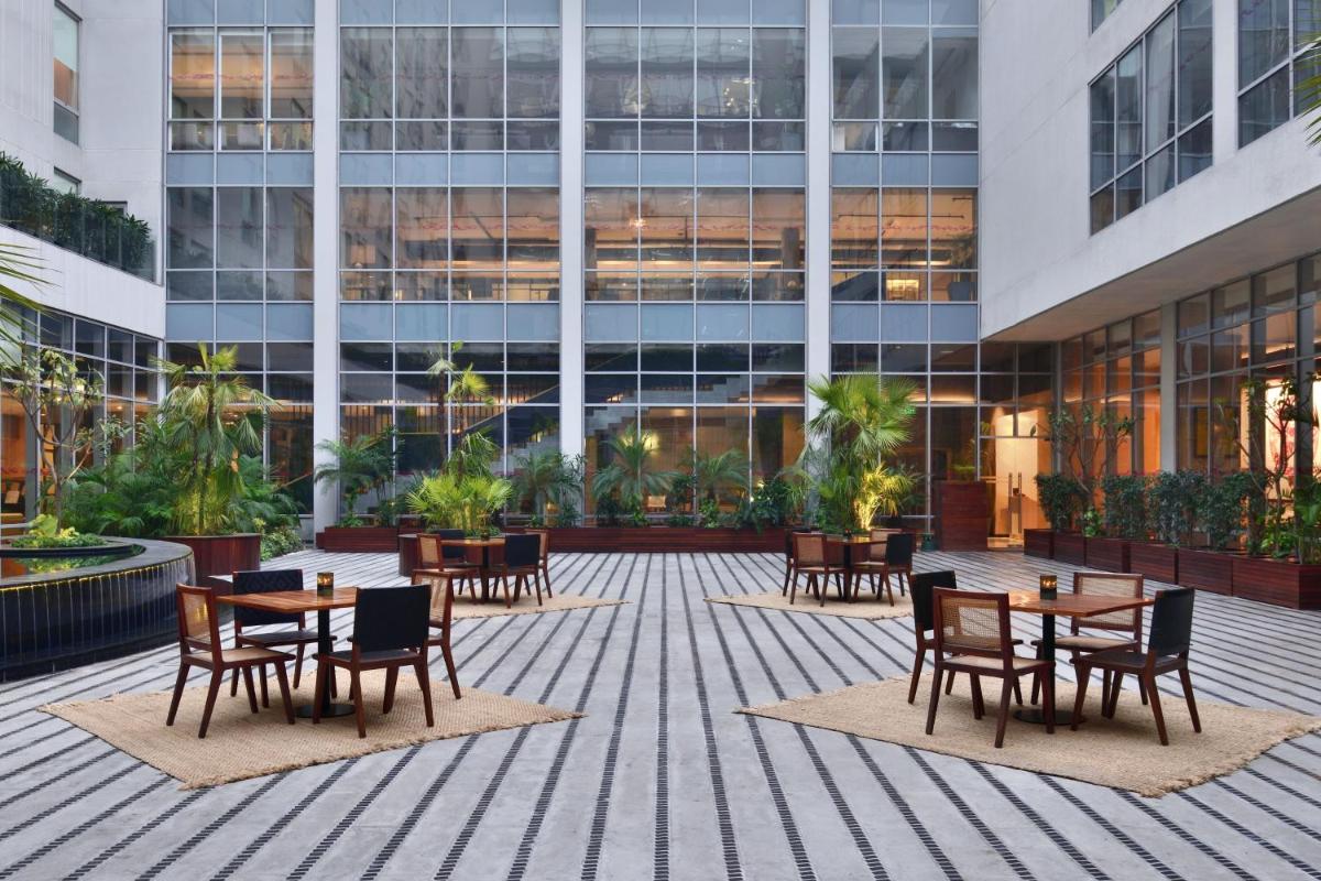 a courtyard with tables and chairs in front of a building at Aloft New Delhi Aerocity in New Delhi a courtyard with tables and chairs in front of a building at Aloft New Delhi Aerocity in New Delhi