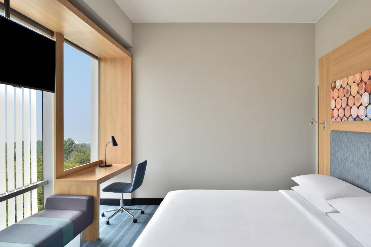 a bedroom with a bed and a desk and a window at Aloft New Delhi Aerocity in New Delhi a bedroom with a bed and a desk and a window at Aloft New Delhi Aerocity in New Delhi