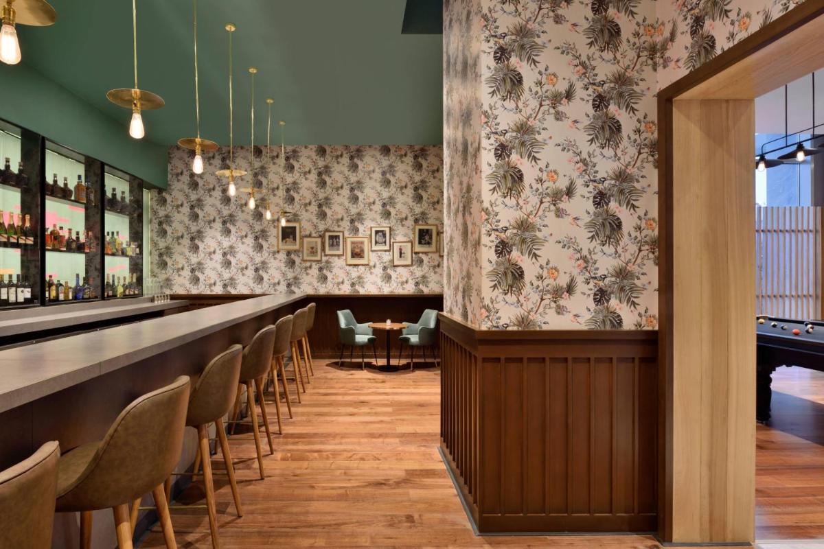 a bar with a row of chairs and a long counter at Aloft New Delhi Aerocity in New Delhi a bar with a row of chairs and a long counter at Aloft New Delhi Aerocity in New Delhi