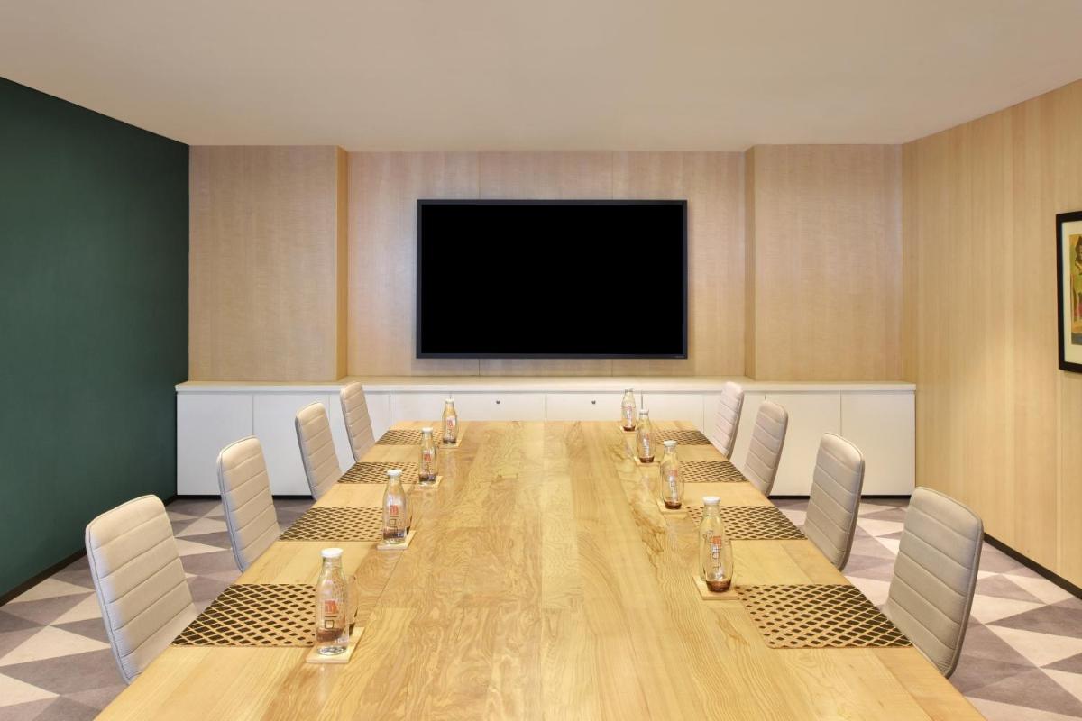 a conference room with a long table and a flat screen tv at Aloft New Delhi Aerocity in New Delhi a conference room with a long table and a flat screen tv at Aloft New Delhi Aerocity in New Delhi