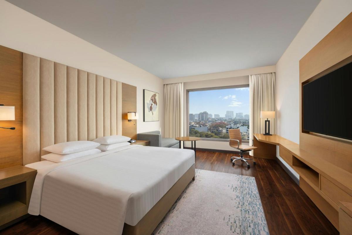 a hotel room with a bed and a flat screen tv at Courtyard by Marriott Gurugram Downtown in Gurgaon