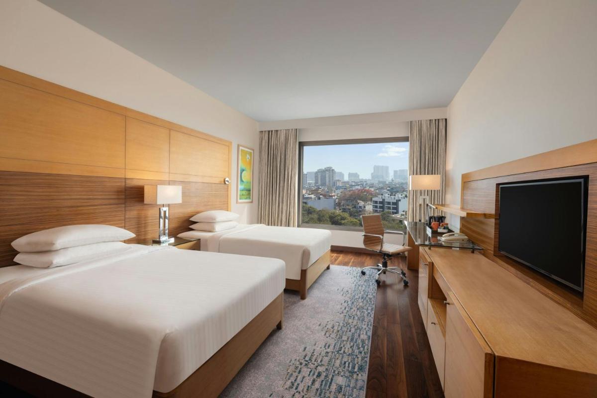 a hotel room with two beds and a flat screen tv at Courtyard by Marriott Gurugram Downtown in Gurgaon