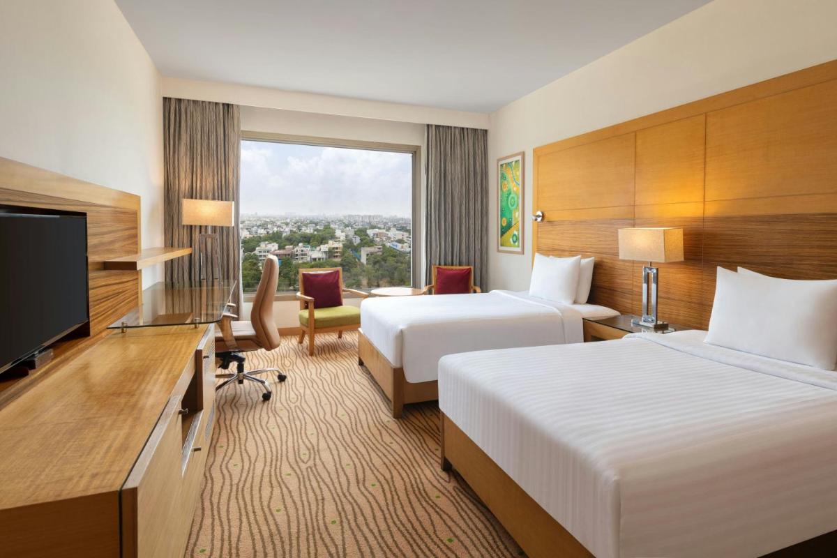a hotel room with two beds and a flat screen tv at Courtyard by Marriott Gurugram Downtown in Gurgaon