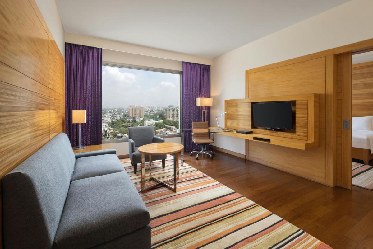 a hotel room with a couch and a television at Courtyard by Marriott Gurugram Downtown in Gurgaon