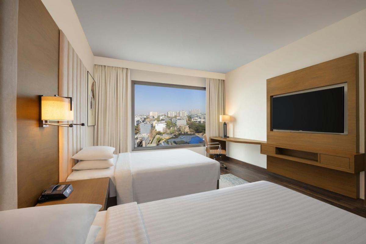 a hotel room with two beds and a flat screen tv at Courtyard by Marriott Gurugram Downtown in Gurgaon