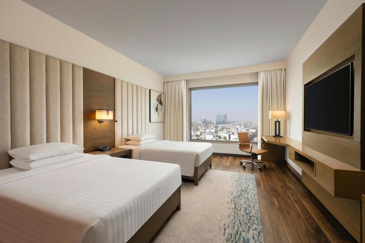 a hotel room with two beds and a flat screen tv at Courtyard by Marriott Gurugram Downtown in Gurgaon