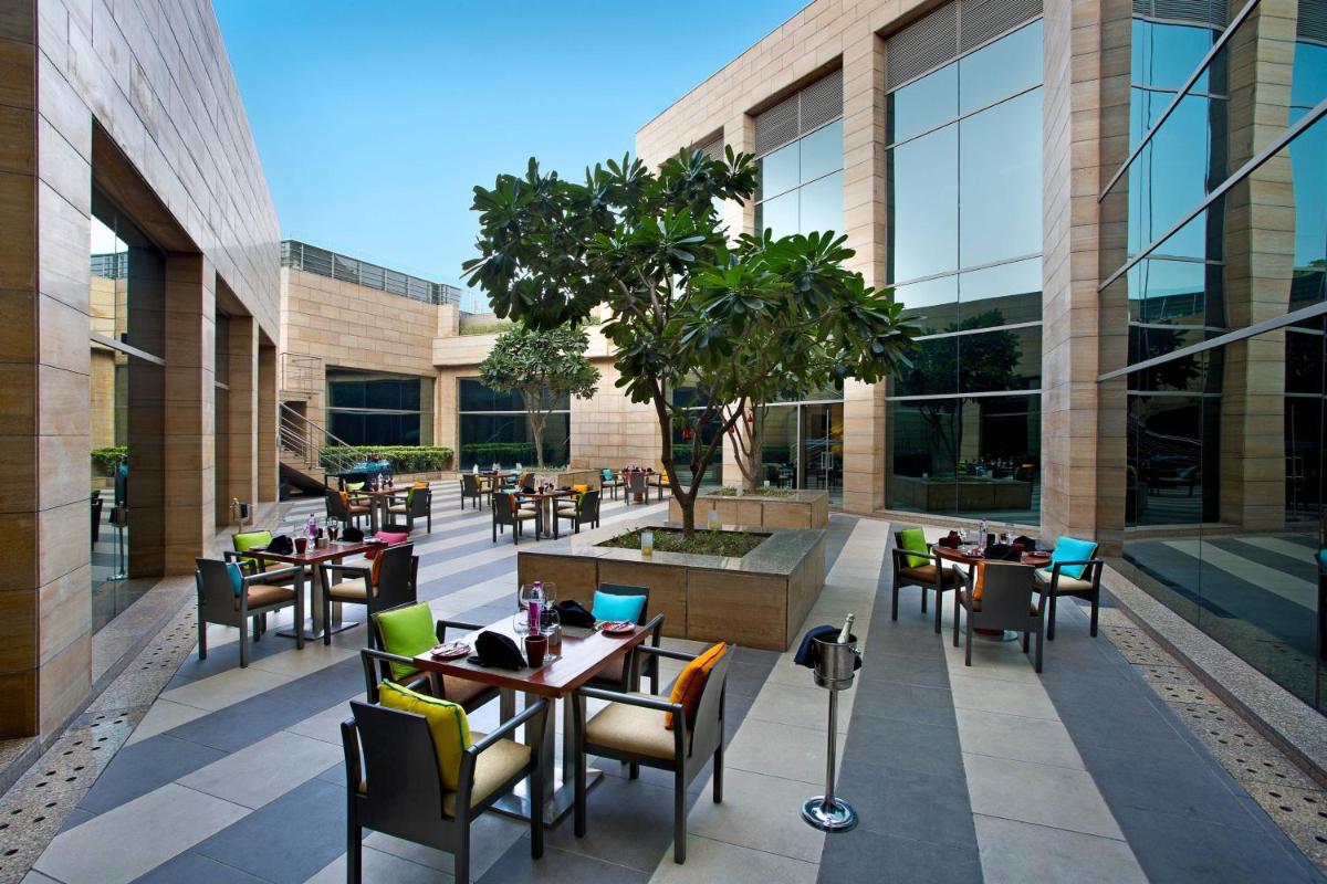 a restaurant with tables and chairs in front of a building at Courtyard by Marriott Gurugram Downtown in Gurgaon