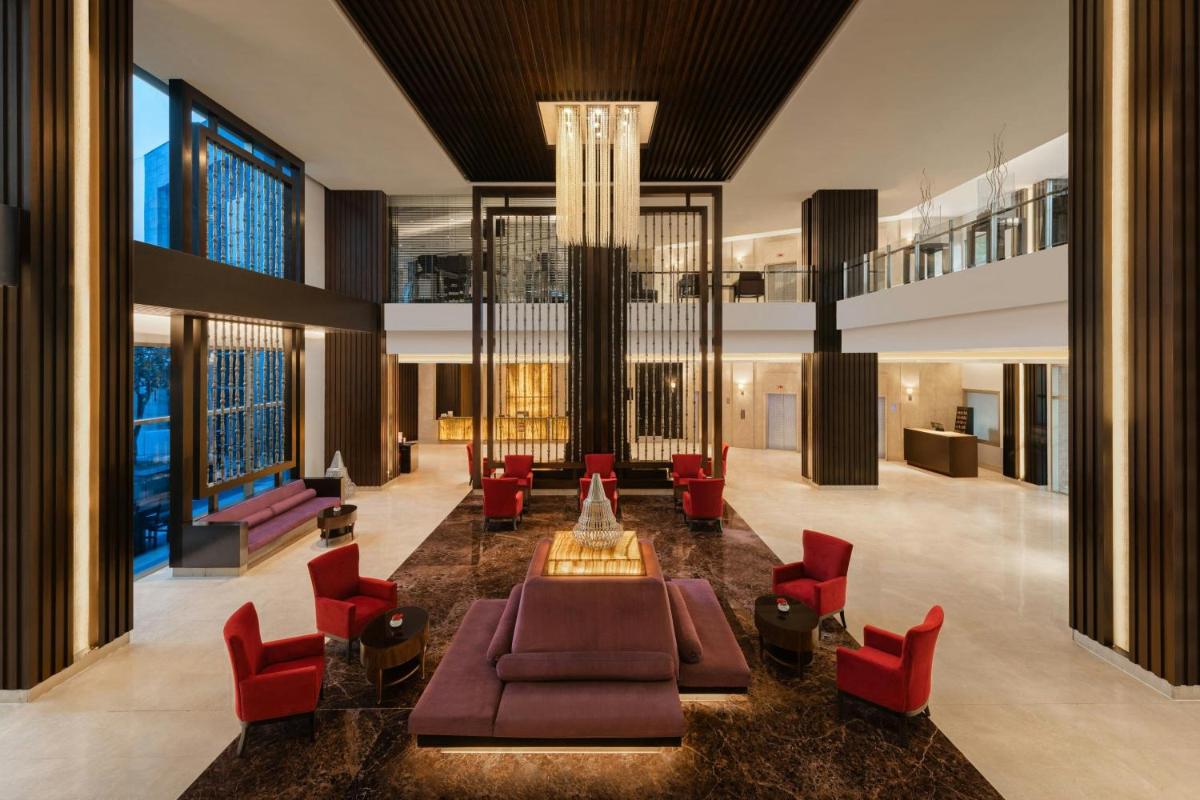 a lobby with red chairs and a couch and a chandelier at Courtyard by Marriott Gurugram Downtown in Gurgaon