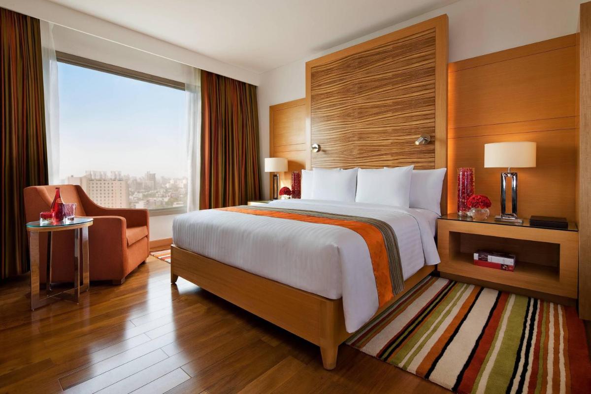a hotel room with a bed and a chair and a window at Courtyard by Marriott Gurugram Downtown in Gurgaon