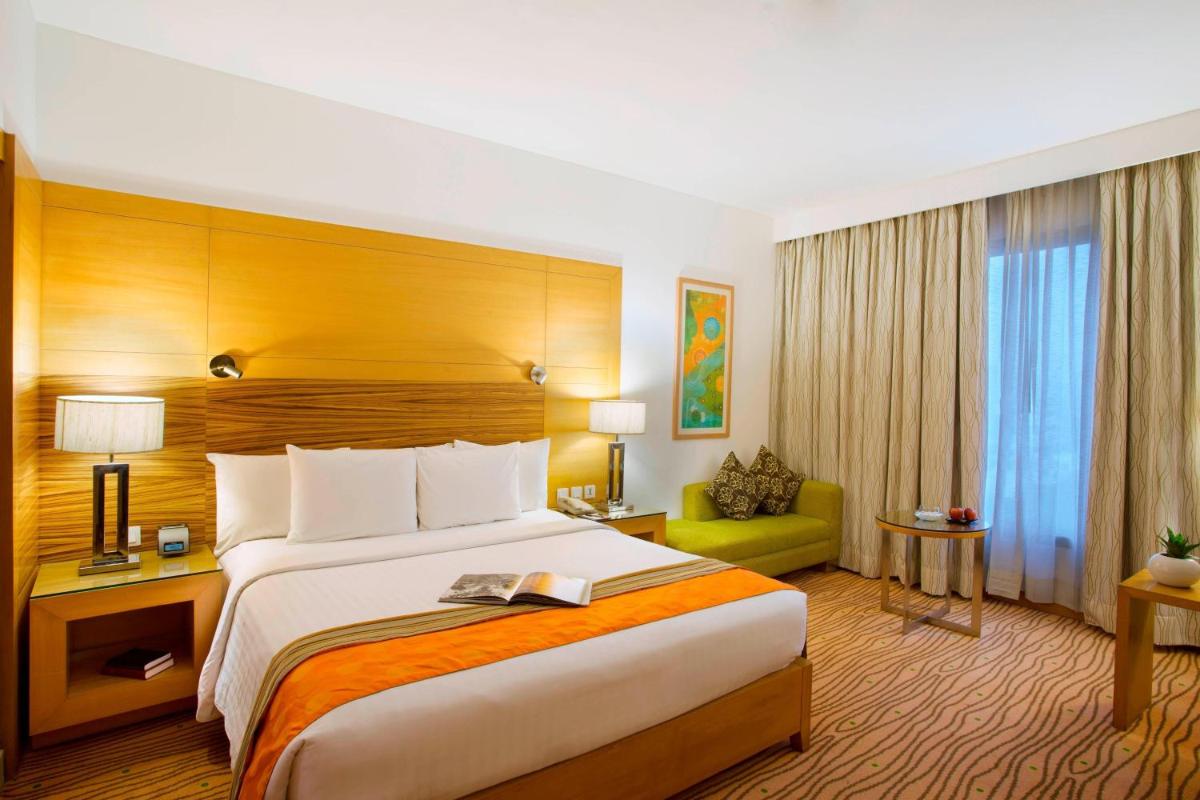 a hotel room with a large bed and a couch at Courtyard by Marriott Gurugram Downtown in Gurgaon