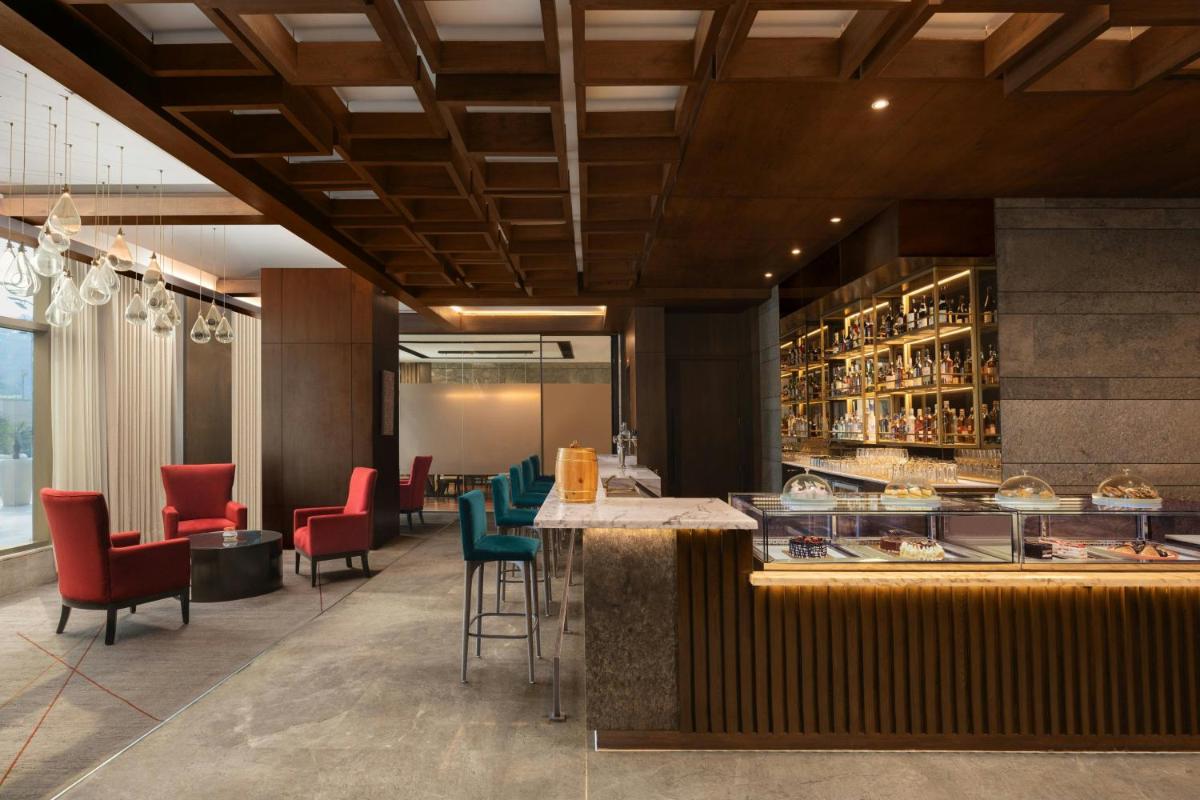 a restaurant with red chairs and a counter with a bar at Courtyard by Marriott Gurugram Downtown in Gurgaon