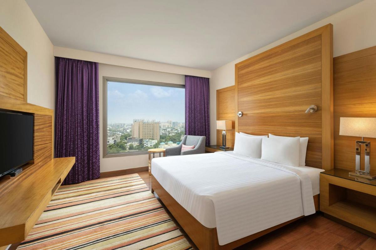 a hotel room with a bed and a large window at Courtyard by Marriott Gurugram Downtown in Gurgaon