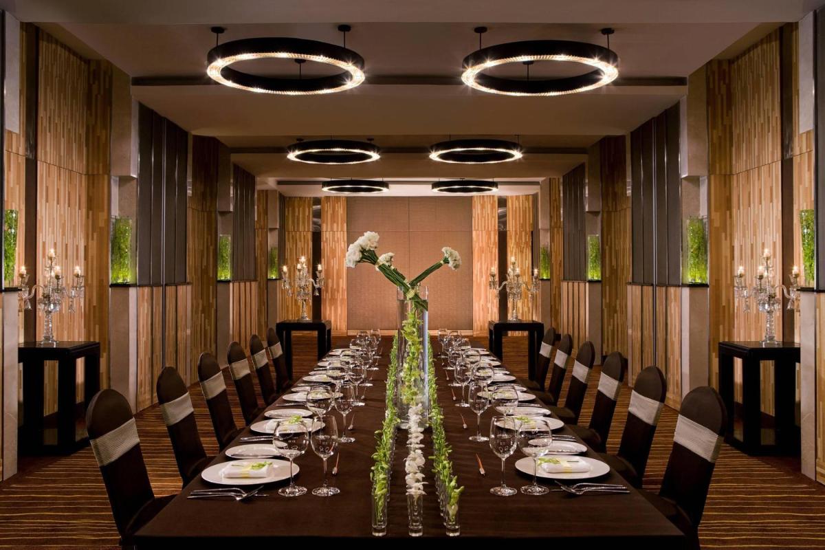 a long table with chairs and a long table with flowers at Courtyard by Marriott Gurugram Downtown in Gurgaon