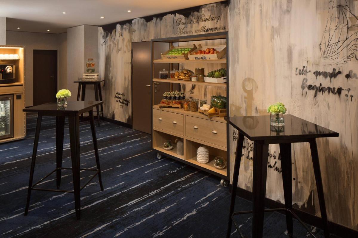 ein Zimmer mit zwei Tischen und einem Regal mit Essen in der Unterkunft Renaissance Hamburg Hotel in Hamburg