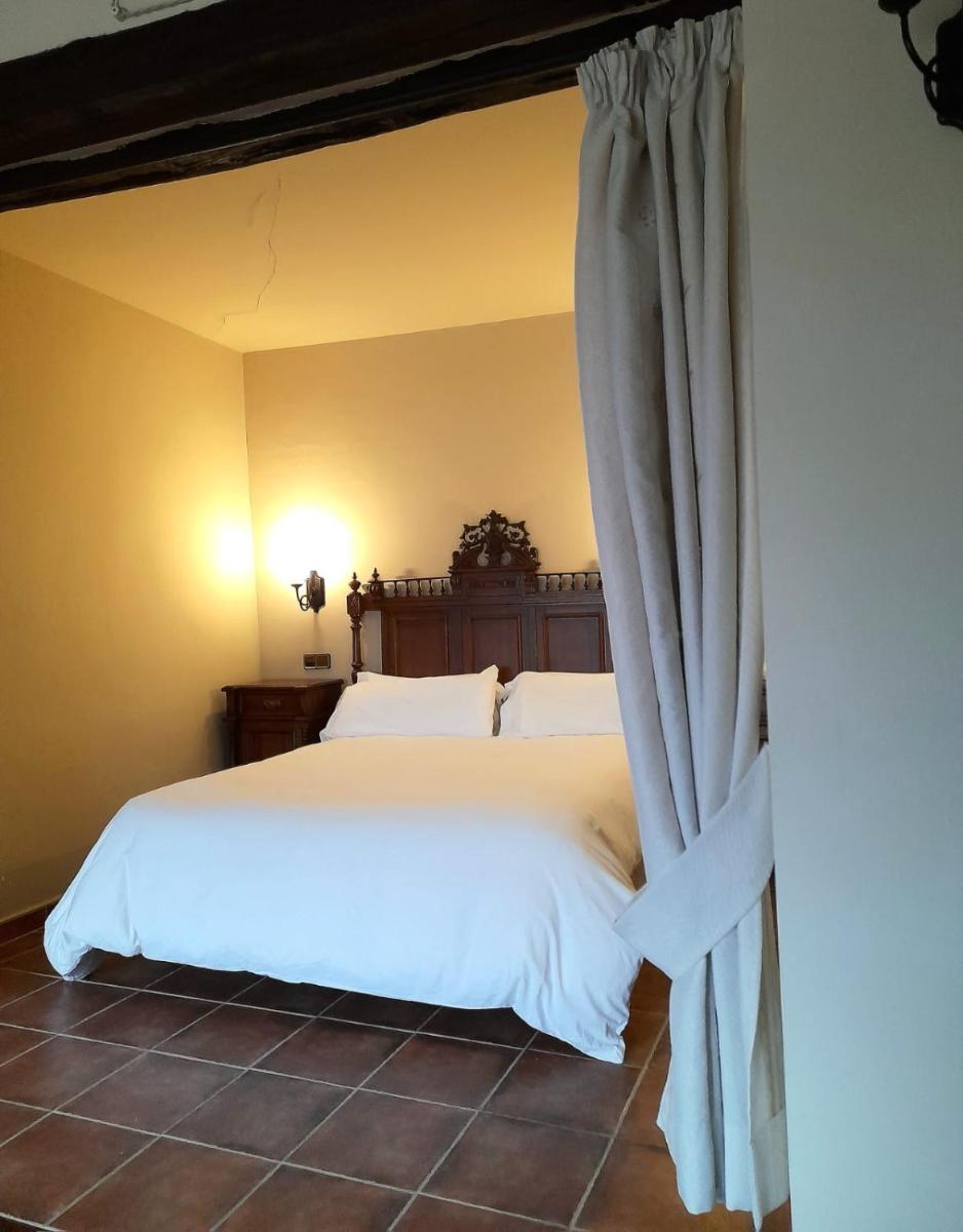 1 dormitorio con cama blanca y cortina en Hotel SPA Don Iñigo de Aragón, en Las Cuevas de Cañart