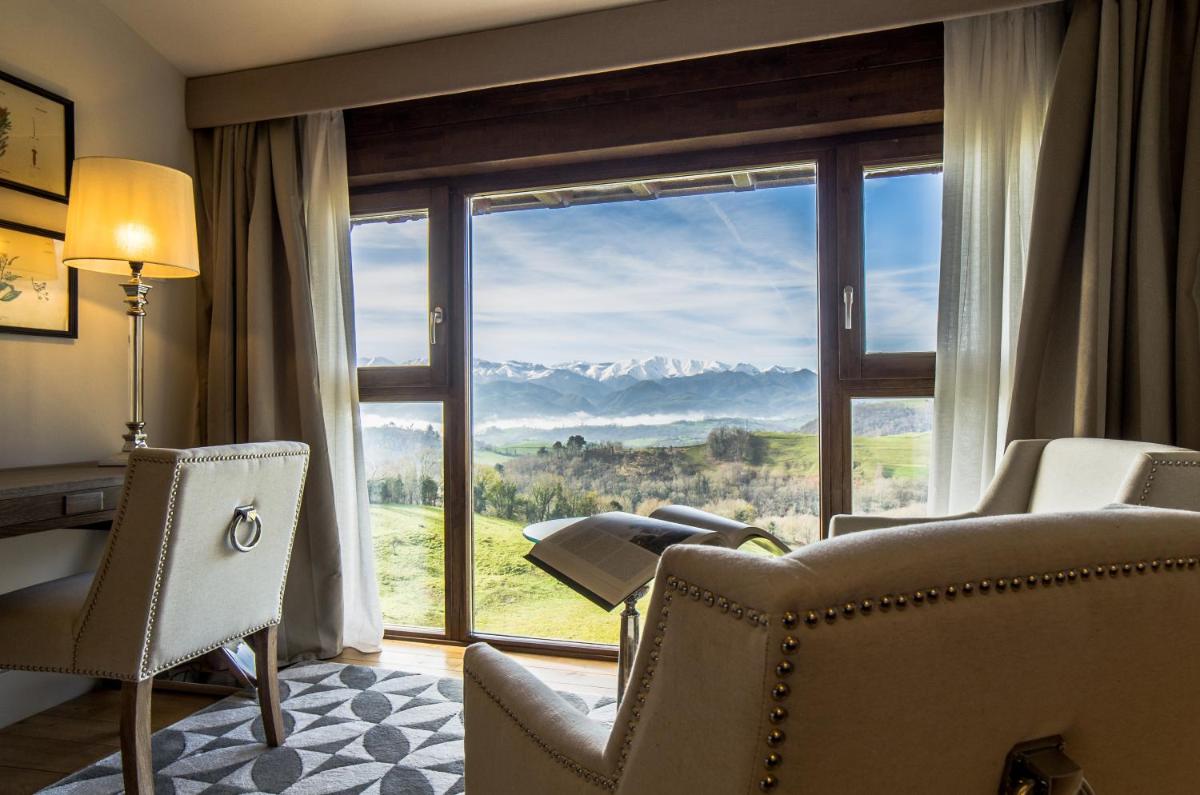Una habitación con una gran ventana con vistas a las montañas. en Puebloastur Eco Resort Hotel & Spa, en Cofiño